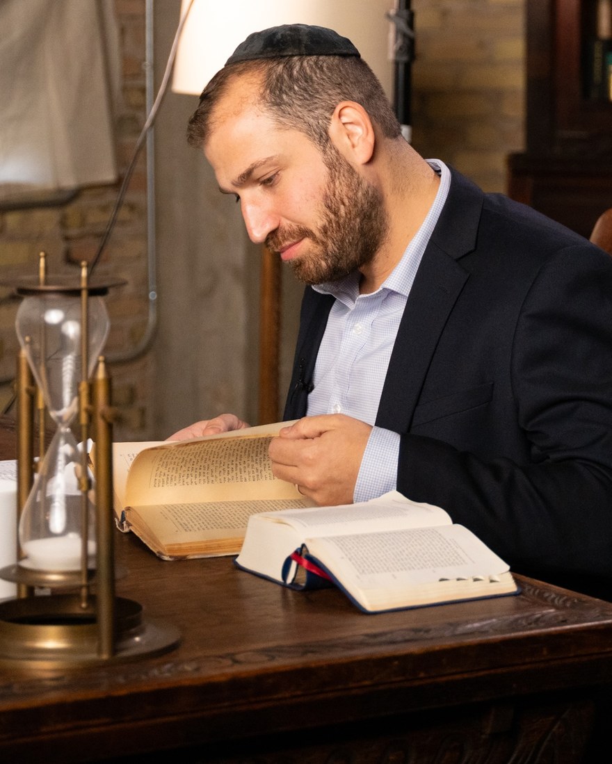 J.J. Kimche studying at his desk, reading from an open volume